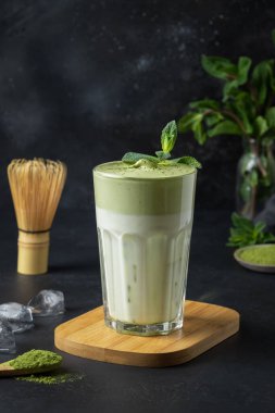 Siyah üzerine bir bardak buzlu Latte Matcha çayı. Dikey format. Kapatın. Moda içeceği.
