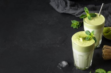 Siyah üzerine bir bardak Dalgona buzlu Latte Matcha çayı. Kapatın. Moda içeceği. Metin için boşluk.