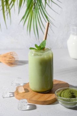 Açık beyaz arka planda buzlu yeşil kibrit sütlü çay. Kapat. Dikey biçim.