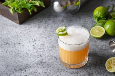 Pisco kokteyli, limonlu viski, yumurta beyazı, gri masada şekerli şurup. Metin için boşluk.