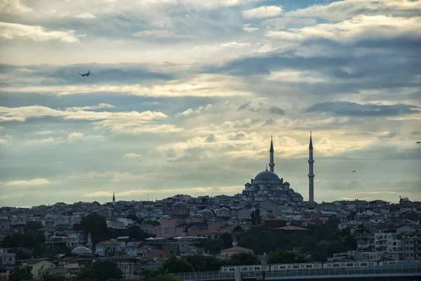 Skyline of Istanbul at sunset with silhouettes of mosques and old buildings in Suleymaniye district. Cityscape of Istanbul with passenger airplane over the ancient downtown in sun lights.