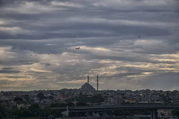 Günbatımında, Süleyman ilçesinde camilerin ve eski binaların siluetleriyle İstanbul 'un silueti. İstanbul 'un antik şehir merkezinde güneş ışığı altında yolcu uçağıyla şehir manzarası. 