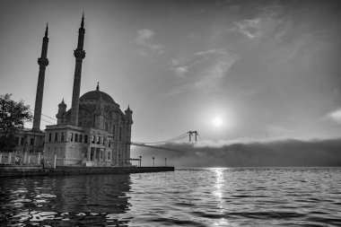 İstanbul 'daki Ortakoy Camii ve Boğaz Köprüsü. Dramatik bir gökyüzü. 15 Temmuz Şehitler Köprüsü sisli