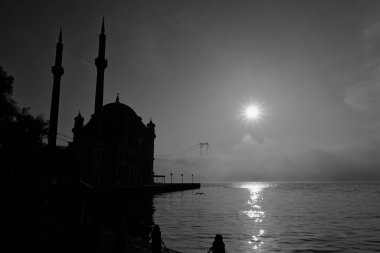 İstanbul 'daki Ortakoy Camii ve Boğaz Köprüsü. Dramatik bir gökyüzü. 15 Temmuz Şehitler Köprüsü sisli. Cami Silueti Skyline.