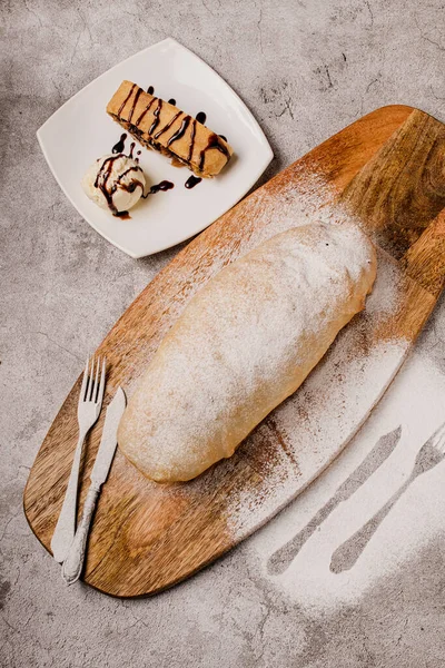 A strudel with apples, dried fruits, nuts on a wooden board — Stock Photo, Image