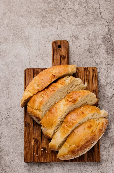 Pieces of round large white bread on a wooden cutting board. — Stock fotografie