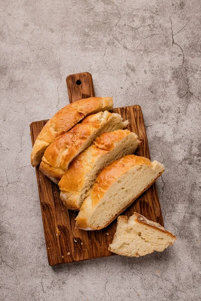 Pieces of round large white bread on a wooden cutting board. — Stock Fotó