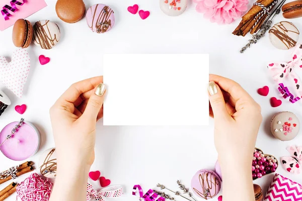 Tangan wanita memegang kartu ucapan putih kosong dengan latar belakang putih dengan dekorasi romantis. flat lay — Stok Foto