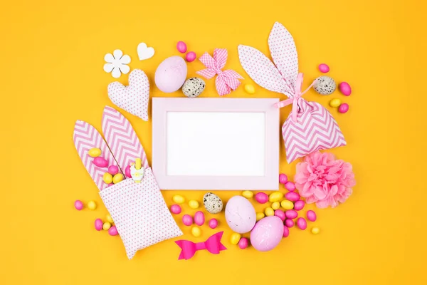 Zdjęcie klatki lub bon upominkowy z Wielkanoc dekoracje z jajka, torba bunny i cukierki na żółtym tle — Zdjęcie stockowe