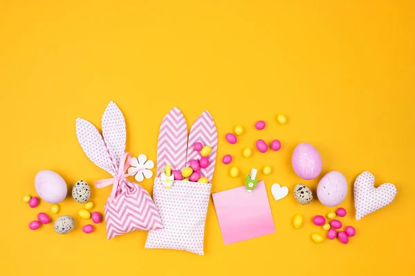 Húsvéti dekoráció, a tojás, a nyuszi zsák és a cukorkát a sárga háttér — Stock Fotó