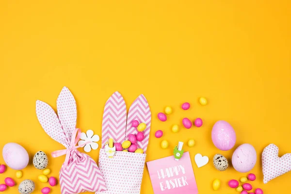 Pasen decoratie met eieren, bunny tas en suikergoed op gele achtergrond — Stockfoto