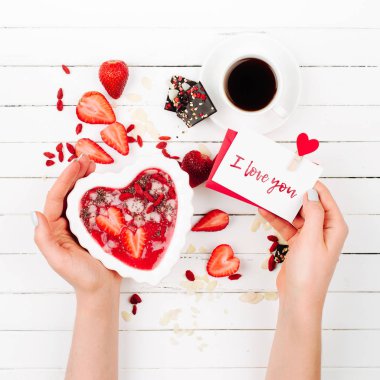 Eller bir çilek yüzlü bir kalp ve Sevgililer kartı şeklinde bir kase içinde tutun. Sevgililer günü. Tatil Kahvaltı