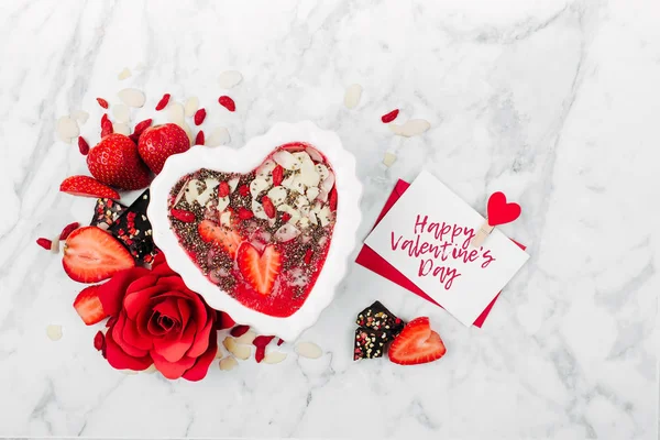 Strawberry smoothie in a bowl in the shape of a heart and valentine  card. Healthy and tasty breakfast on marble background — Stock Photo, Image