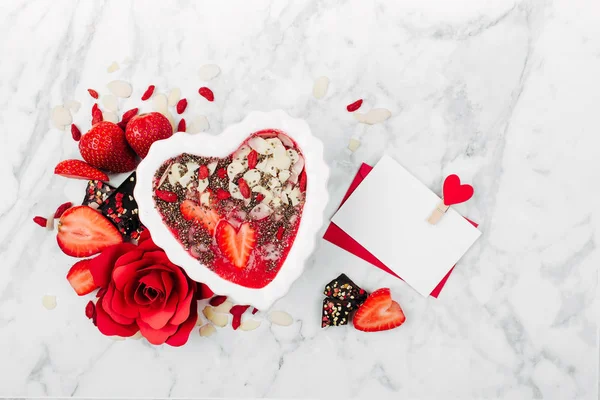 Frullato di fragole in una ciotola a forma di cuore e cartolina di San Valentino. Colazione sana e gustosa su sfondo di marmo — Foto Stock