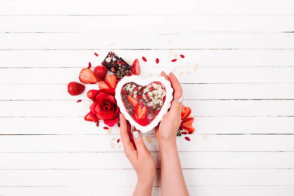 Female hands hold a strawberry smoothie in a bowl in the shape of a heart. Valentine's Day. Holiday breakfast — Stock Photo, Image