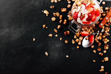 Sağlıklı Kahvaltı, berry smoothie çilek, badem pul ve kopya alanı siyah zemin üzerine granola ile tepesinde bir cam kavanoz içinde