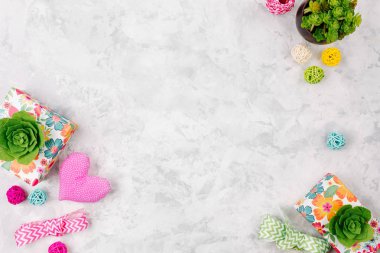 Bahar süslemeleri ile güzel çalışma alanı: hediyeler, yeşil succulents, kalp, kurdeleler ve gri arka plan üzerinde rattan topları. Kopya alanı 