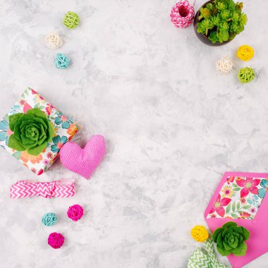 Güzel arka plan bahar süslemeleri ile: hediyeler, yeşil succulents, kalp, kurdeleler ve rattan topları. Kopya alanı 