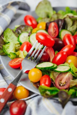 Bir çatal domatese kapatın. Sağlıklı salata otlar ve kırmızı ve sarı kiraz domates.