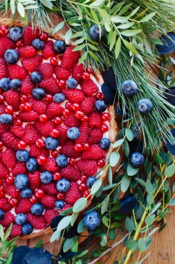 Ahududu ve yaban mersini ile Berry tart çiçeklerle süslenmiş ve dalları yaprakları ile yakın çekim