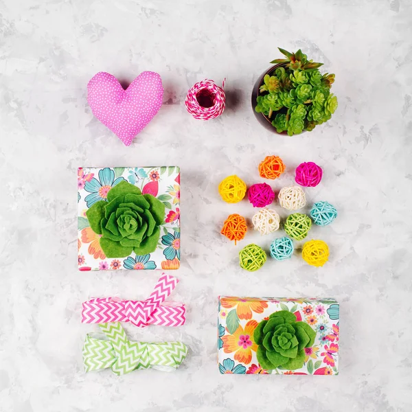 Schöne Geschenke mit grünen Sukkulenten, Herzen, Bändern und Rattanbällen verziert. Hintergrund: Frühling — Stockfoto