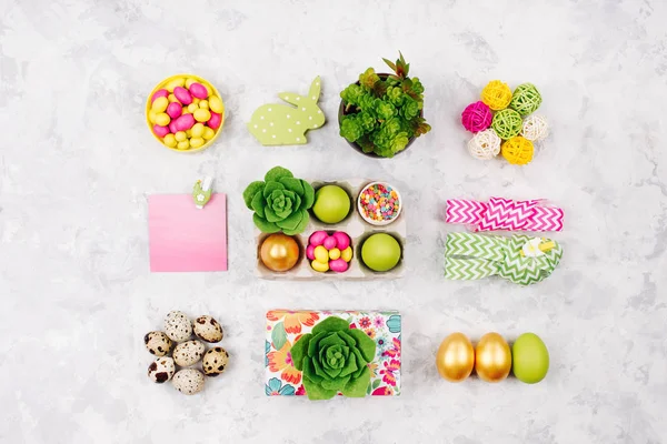 Квартира стильный набор: розовый, желтый и зеленый Пасхальные украшения, яйца, конфеты и соккуленты в лоток бумаги и другие весенние украшения — стоковое фото