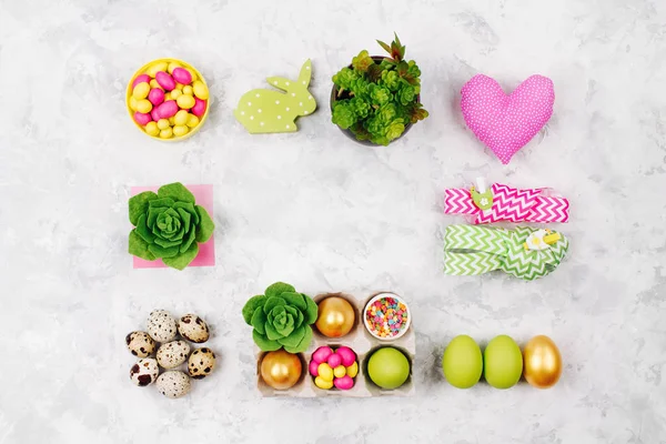 Plat leggen stijlvolle set: roze, gele en groene Pasen versieringen, eieren, snoep en vetplanten in de papierlade, linten, konijn en andere decoratie lente met kopiëren ruimte — Stockfoto