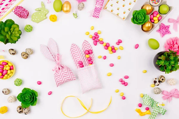 Espacio de trabajo con decoración de Pascua y bolsas de regalo de conejo con dulces. Fondo de primavera. Piso tendido, vista superior — Foto de Stock
