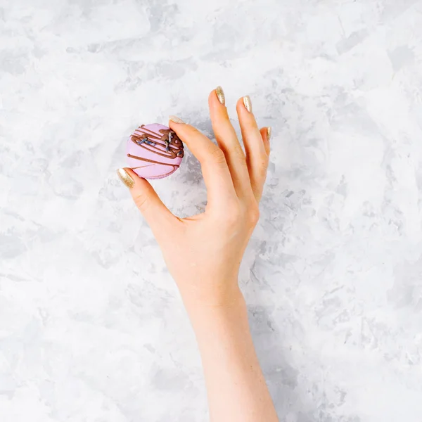 Γυναικείο χέρι κρατά λεβάντα ζάχαριν διακοσμημένα με σοκολάτα σε γκρι φόντο. Μινιμαλισμός — Φωτογραφία Αρχείου