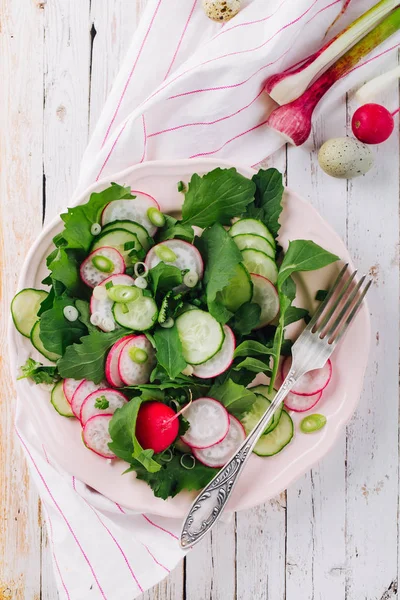 Gezonde zelfgemaakte salade met radijs, komkommer en rucola op de houten achtergrond — Stockfoto