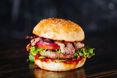 Burger pastırma, et, domates ve marul üzerine ahşap arka plan ile. Yakın çekim