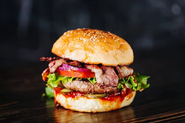 Hambúrguer com bacon, carne, tomate e alface sobre fundo de madeira. Fechar — Fotografia de Stock