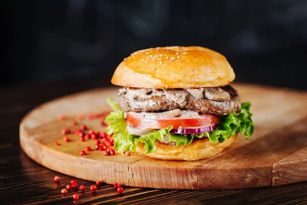 Burger with mushrooms, meatballs, tomato and lettuce on a wooden cutting board — Stock Photo, Image