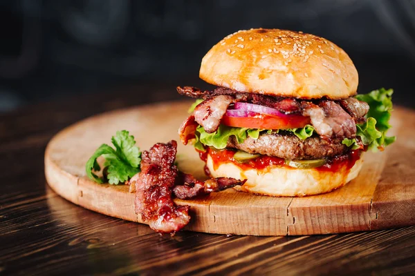 Burger con pancetta, carne, pomodoro e lattuga su fondo di legno. Da vicino. — Foto Stock