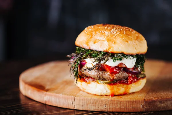 Burger with  meat, tomato, dill and cheese sauce on wooden background. Close up. Copy space — Stock Photo, Image