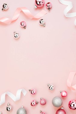parlak Noel topları ve flamalar üzerinde pembe bir arka plan, üstten görünüm