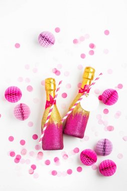 pembe ve altın glitter ve pembe kağıt topları dekore edilmiş iki şampanya şişeleri 