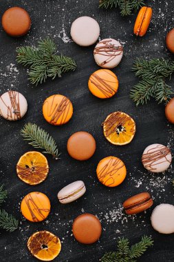 Portakal, macaroons ve köknar dallarında gri bir arka plan deseni 