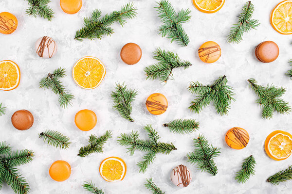 pattern of delicious macaroons, dry oranges and fir twigs on white background 