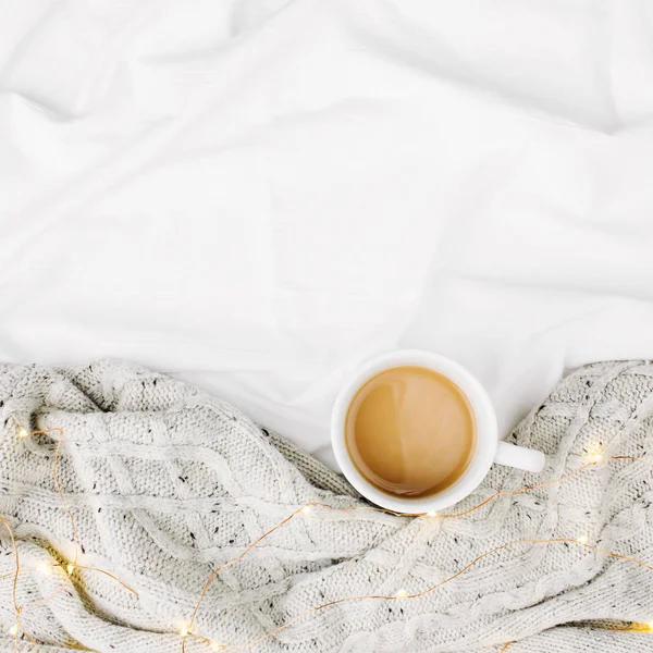 Cup of coffee on bed with warm plaid, copy space