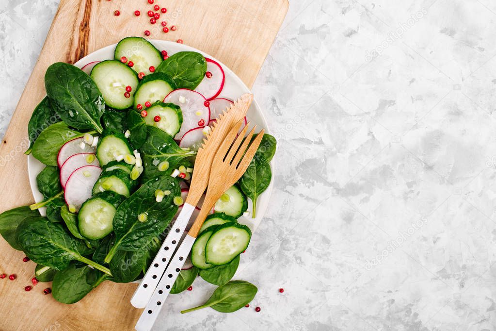 healthy salad with radish, cucumber and spinach on wooden board