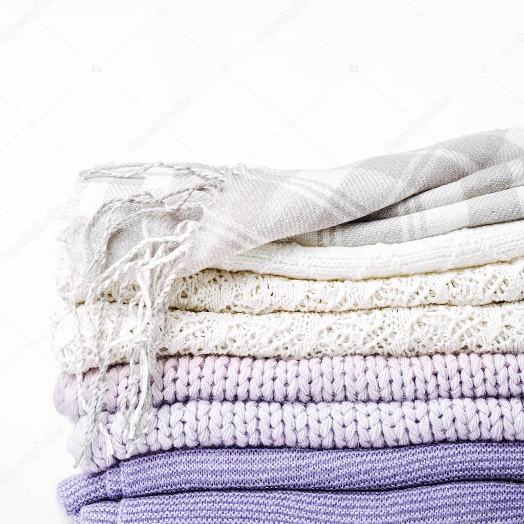 Stack of warm clothes sweaters and plaid isolated on white background