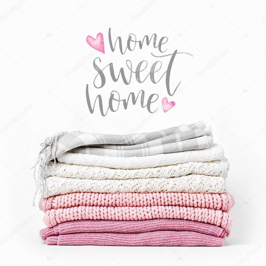 pile of knitted clothes and text Home Sweet Home on white background 
