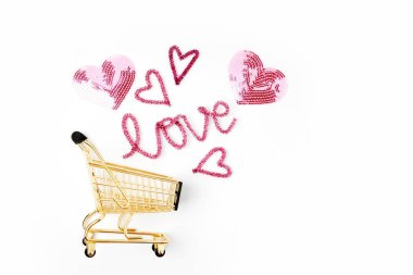 Alışveriş sepeti ve beyaz arka plan üzerinde izole aşk yazı pembe kalpler closeup