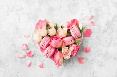 Mermer masa üzerinde çiçekler ve kabın içinde pembe macaroons ve üstten görünüm