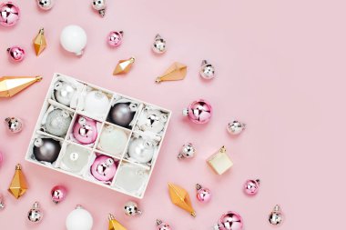 Parlak Noel topları kutusu ve altın kristalleri üstten görünüm pembe bir arka plan üzerinde