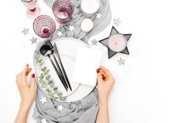 Kağıt ve kadehlerin çatal, bıçak, kaşık ve beyaz arka plan üzerinde izole mum tutan eller Üstten Görünüm