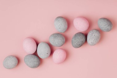 Pastel arka plan üzerinde soluk pembe ve gri Paskalya yumurtaları grup. Düz yatıyordu 