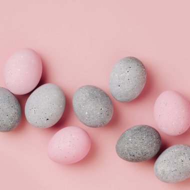 Pastel arka plan üzerinde soluk pembe ve gri Paskalya yumurtaları grup. Düz yatıyordu 