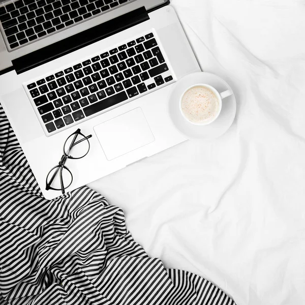 工作空间与笔记本电脑和咖啡在床上 早上的概念 平躺在床上 — 图库照片